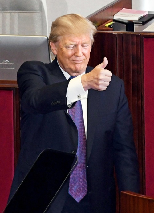 ８日午前、国会本会議場で演説を終えたトランプ米大統領が、起立拍手を送る議員に親指を立てて応えている。