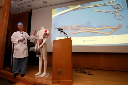 イ・グクジョン教授が今月１５日に開かれた１次ブリーフィングで手術中に発見した回虫について説明している。