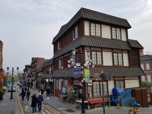 日本式の建物が並ぶ商店街を観光客が歩いている。