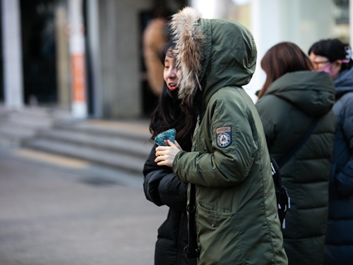 手には使い捨てカイロ、フードをすっぽりかぶり防寒対策をする人もいました。