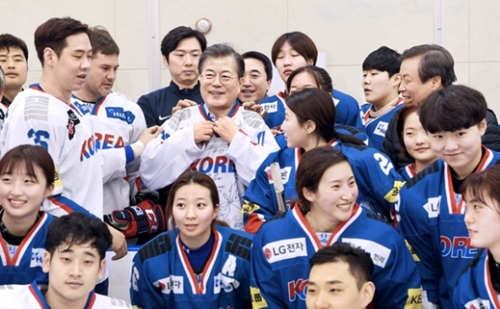 文在寅（ムン・ジェイン）大統領が１７日、忠清北道鎮川（ジンチョン）韓国代表選手村を訪問し、男女アイスホッケー選手団から受けた記念ユニホームを着て記念撮影をしている。（青瓦台写真記者団）