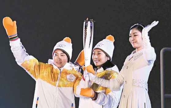 ９日の２０１８平昌冬季オリンピック開会式で、南北女子アイスホッケー選手のチョン・スヒョン（左）とパク・ジョンアが聖火最終走者のキム・ヨナと観客に手を振っている。（中央フォト）