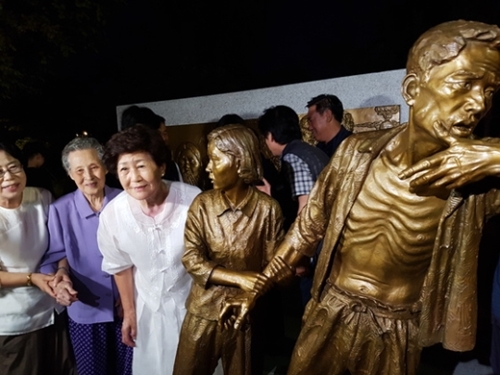 日本による植民地時代に強制徴用された労働者を象徴する強制徴用労働者像「解放の予感」が２０１７年８月１２日、全国で初めて仁川の富平公園に設置された。銅像の「娘」のモデルとなったチ・ヨンレさん（左端）と「父」のモデルのイ・インヒョンさんの娘イ・スクチャさん（左から２人目）が銅像の前で記念撮影をしている。