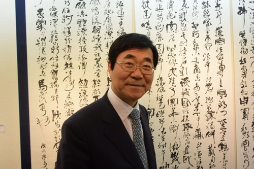 東京の銀座渋谷画廊で９日、自身の「沁穏混融体」で書いた「弄筆千字文」の前に立つ書芸家の全正雨（チョン・ジョンウ）氏。