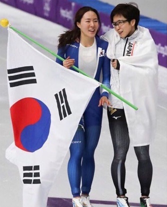 １８日、江原道江陵スピードスケート競技場で行われた平昌冬季五輪スピードスケート女子５００メートル競技の後、肩を寄せ合いながらリンクを回る韓国の李相花（左）と日本の小平奈緒。