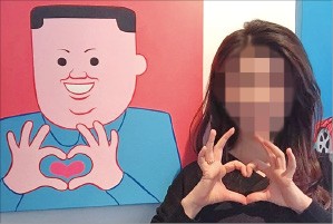 北朝鮮の最高指導者である金正恩（キム・ジョンウン）委員長をモチーフに描いた絵の前で撮影した「ハート認証ショット」がソーシャル・ネットワーキング・サービス（ＳＮＳ）で広がり議論を呼んでいる。