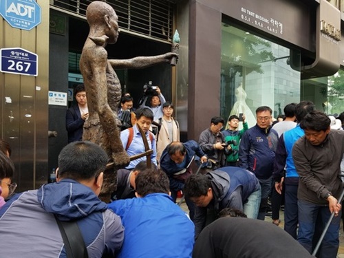 市民団体の会員らが１日午前９時４０分、日本総領事館前に労働者像を移している。