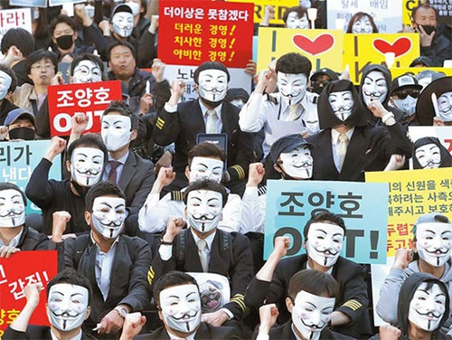 大韓航空の職員が４日、ソウル世宗文化会館前で開かれた「趙亮鎬一家退陣とパワハラ根絶のための第１回光化門ろうそく集会」でスローガンを叫んでいる。彼らは抵抗デモの象徴である「Ｇｕｙ　Ｆａｗｋｅｓ」の仮面をかぶって参加し、趙会長一家の経営退陣とパワハラに対する当局の厳重な処罰を促した。