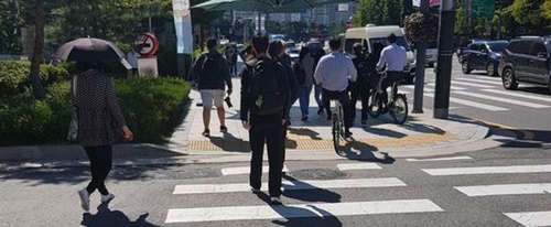ソウル市公共自転車「タルンイ」に乗った二人の市民が２７日、ソウル中区（チュング）のソウル市庁前の横断歩道を渡り、歩行者の間を走っている。自転車の歩道・横断歩道運行は、罰金３万ウォンが賦課される「違法」だ。
