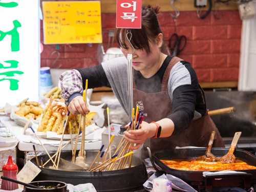 屋台グルメで有名な広蔵市場（クァンジャンシジャン）の「うまいもん通り」には、リーズナブルで美味しい韓国グルメを求めて、国内外からたくさんの観光客が訪れます。