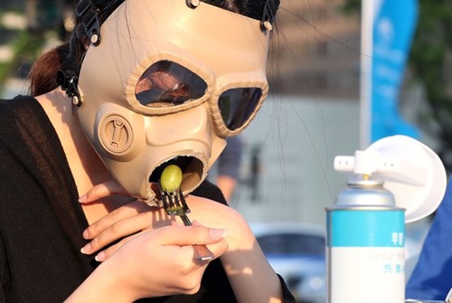 １４日、ソウル光化門広場で開かれた「粒子状物質の中のダイニング」行事で、参加者が防毒マスクをかぶって食事をする姿を演出している。