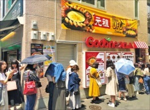 東京新大久保通りにある飲食店「クプネチキン（Ｇｏｏｂｎｅ）」の前に日本人が「チーズタッカルビ」を食べるために列を作っている。