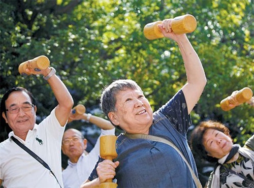 木製ダンベルを持って体操する日本の高齢者（中央フォト）