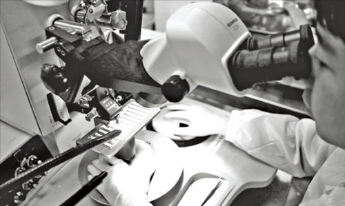 韓国光技術院の研究員が電子顕微鏡で光ファイバー素材を観察している。　［写真　韓国光技術院提供］