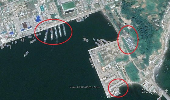  昨年８月に撮影された衛星写真には海へ向かって埠頭に停泊している大型艦艇の数が大きく増え（左側円内）、海軍艦艇の修理のための上架と軍テントまたは行政施設と推定される建物（右下）を新設したことがわかった。［グーグルアース　キャプチャー］