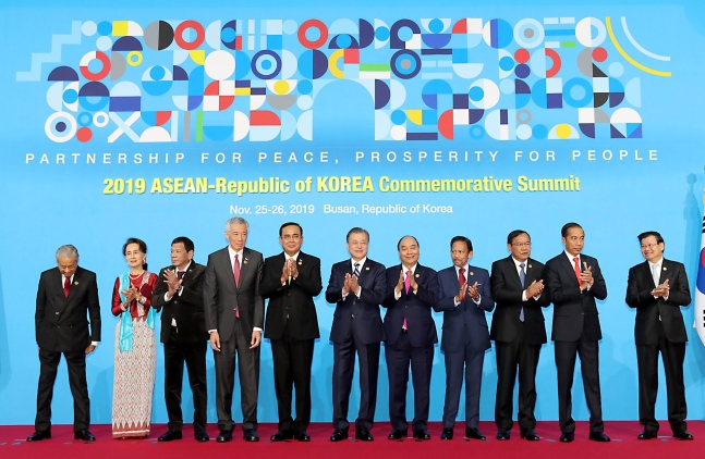 文在寅大統領が１１月２６日午前に釜山のＢＥＸＣＯで開かれた２０１９韓国・ＡＳＥＡＮ特別首脳会議で出席者と記念撮影をした後拍手している。左からマレー氏はのマハティール首相、ミャンマーのスー・チー国家顧問、フィリピンのドゥテルテ大統領、シンガポールのリー・シェンロン首相、タイのプラユット首相、文大統領、ベトナムのフック首相、ブルネイのボルキア国王、カンボジアのプラック・ソコン副首相兼外相、インドネシアのジョコ大統領、ラオスのトンルン首相。［写真　２０１９韓国・ＡＳＥＡＮ特別首脳会議］