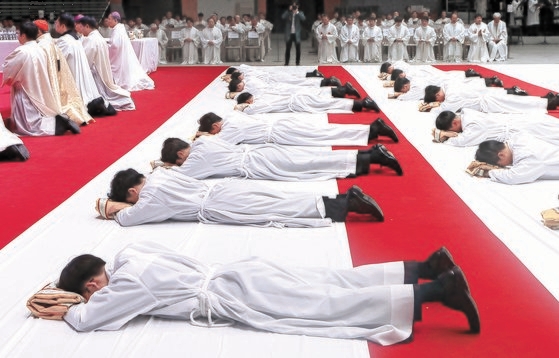 ６日、韓国のカトリックソウル大教区副祭叙品式がオリンピック体操競技場で廉洙政（ヨム・スジョン）枢機卿の主礼で行われ、副祭授品者が祭壇の前にうつ伏せになって祈りを捧げている。チェ・チョンドン記者