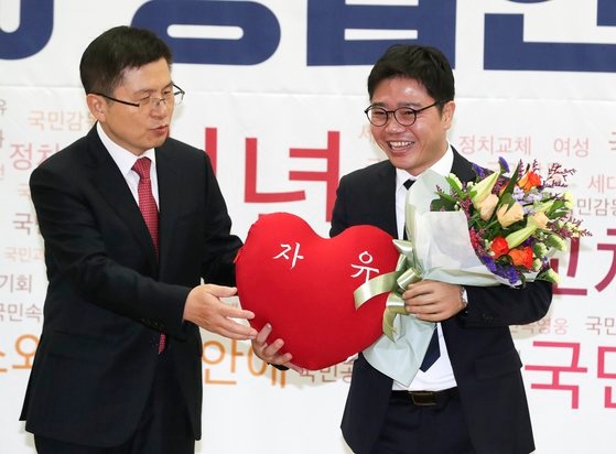 自由韓国党の黄教安（ファン・ギョアン）代表（左）が１月８日国会議員会館で開かれた「２０２０招聘人材歓迎式」で脱北者出身の人権運動家、チ・ソンホ氏に花束とクッションを渡している。