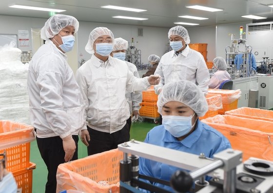 洪楠基副首相兼企画財政部長官（左から２人目）が先月、京畿道安城のマスクメーカーのＫＭを訪問し、生産現場を視察して関係者から説明を聞いている。［写真　企画財政部］