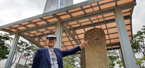 申福龍（シン・ボクリョン）元教授が「恥辱碑」と呼ばれる三田渡碑の前に立っている。後方には１２３階建てのロッテワールドタワーが見える。　チャン・セジョン記者
