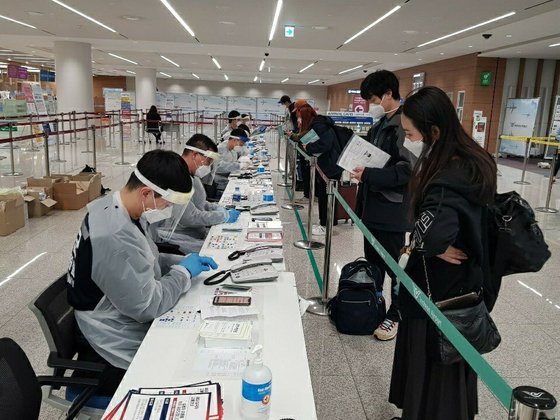 仁川空港に派遣された軍人が入国者の検疫書類を確認して自宅隔離アプリを設置している。［写真　国防部］
