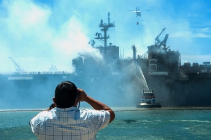 米国市民が米海軍の強襲揚陸艦であるボノム・リシャール（ＬＨＤ６）の火災鎮圧作業を双眼鏡で見守っている。［写真　米海軍］