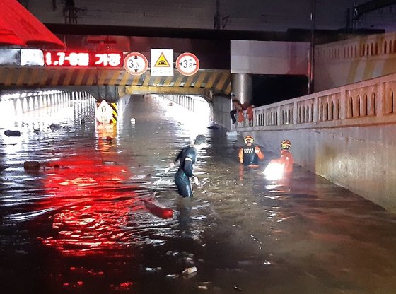 ２３日、大雨が降った釜山東区草梁洞釜山駅付近の第１地下車道に出動した消防隊員が救助作業を行っている。［写真　釜山消防災難本部］