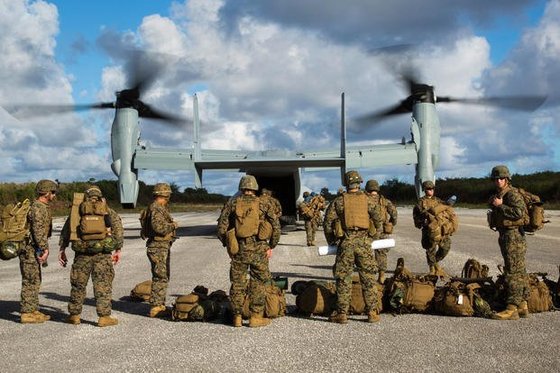 米海兵隊が垂直離着陸輸送機ＭＶ－２２オスプレイに乗るために待機している。［写真　米海兵隊］