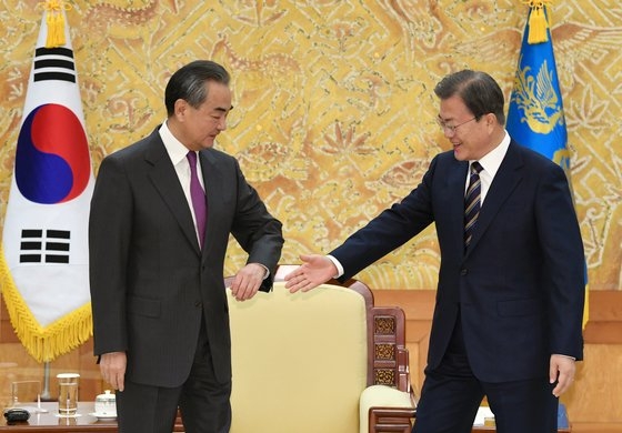 中国の王毅外交部長に対し、肘タッチの代わりに手を差し出した韓国の文在寅大統領。［写真　青瓦台写真記者団］