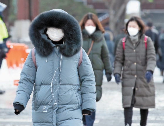 ７日午前、ソウル光化門（クァンファムン）で一人の市民がコートについたフードを目深にかぶって出勤している（左）。イム・ヒョンドン記者
