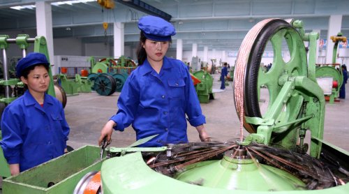 北朝鮮の女性労働者が、電力ケーブル生産設備を調べている。［中央フォト］