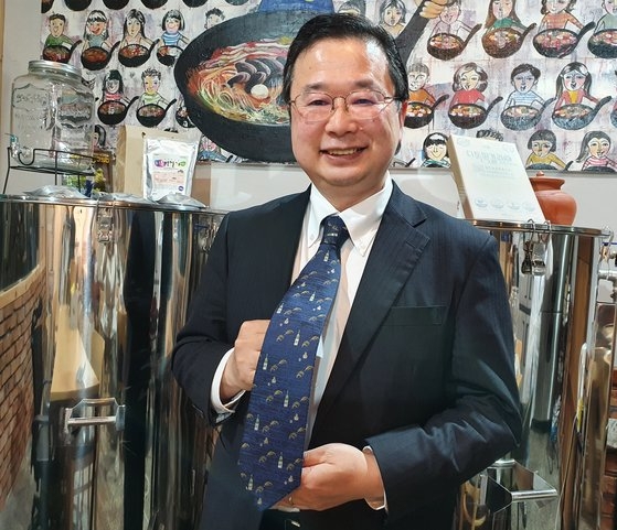 全州（チョンジュ）マッコリ工場を訪問した在韓日本大使館公報文化院長の中條一夫氏。ネクタイを持ち上げて見せているが、酒を醸造する材料の米と、酒瓶が描かれているからだった。酒文化の探訪ということで、わざわざこのネクタイを選んだとのことだ。チョン・スジン記者