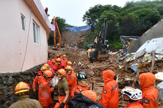 梅雨前線の影響で韓国南部地方に大雨が降った６日、全南光陽市津上面の土砂崩れの現場で救助隊員が遺体で発見された埋没者を移している。フリーランサーのチャン・ジョンピル