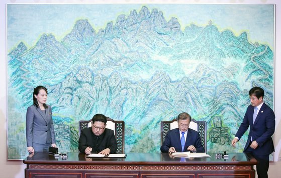 文在寅大統領（右から２番目）と金正恩北朝鮮朝鮮労働党総書記（左から２番目）が２０１８年４月２７日、南北首脳会談で韓半島の平和と繁栄、統一に向けた板門店宣言文に署名している。［写真　青瓦台写真記者団］
