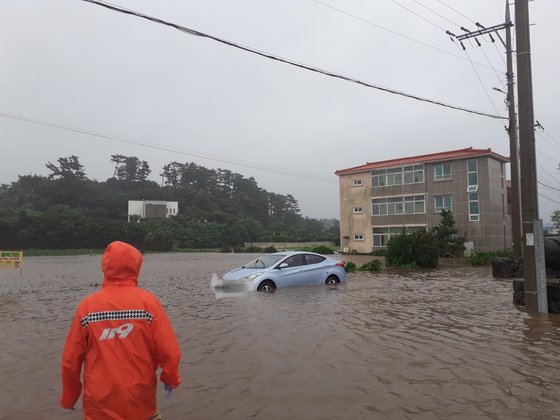 １７日午前７時９分、済州市朝天邑の道路が冠水して車両が孤立し、消防隊員が救助している。　写真＝済州道消防安全本部