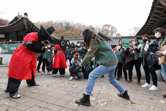 韓国民俗村でイカゲームに登場するめんこを体験しているシンガポールからの観光客　（写真　文化体育観光部）