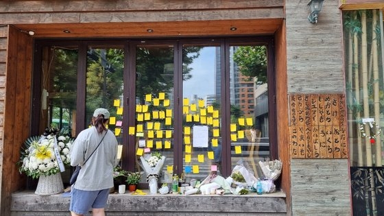 ９月２７日、ソウル麻浦（マポ）にある居酒屋の女性社長が運営していた店舗のガラス壁に市民が残した追慕メモが貼り付けられている。その下に置かれた小さな花輪のリボンには「自営業者のご冥福をお祈りします」と書かれている。チョ・ガンス記者