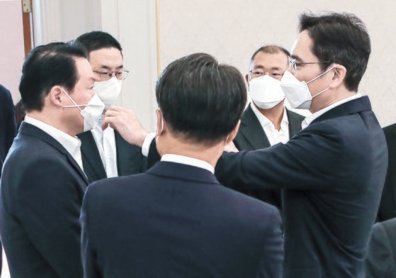 李在鎔サムスン電子副会長（右）が２７日に青瓦台で開かれた青年雇用創出事業「青年希望ＯＮ」参加大企業代表招請昼食懇談会で崔泰源ＳＫ会長（左）のＸ字になったマスクのひもを直している。左から２人目は具光謨ＬＧ会長、右から２人目は鄭義宣現代自動車会長。　キム・ソンリョン記者