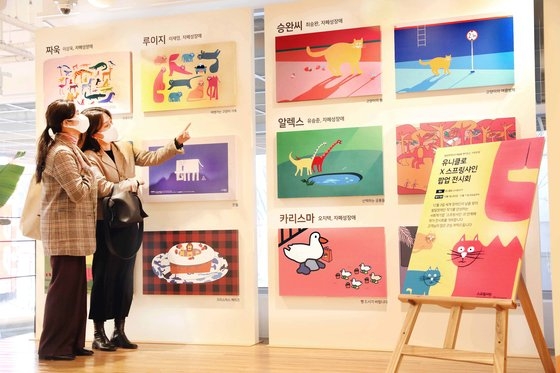 昨年１２月、韓国のユニクロ新沙店で買い物客が発達障がいを持つアーティストのポップアップ展を鑑賞している。［写真　ユニクロ］