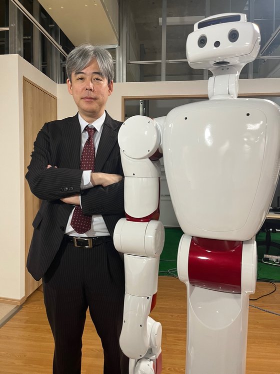 世界で初めて人間型ロボットを開発した早稲田大学で人とともにする「パートナーロボット」を研究している尾形哲也ＡＩ研究所長。尾形所長の横に並んで立っているロボットは最近玉子料理を学んでいる。身長１６６センチに体重は約１５０キロ。ディープラーニング技術を利用し自分で判断してタオルをたたんだり簡単な料理ができる。［写真　キム・ヒョンイェ東京特派員］