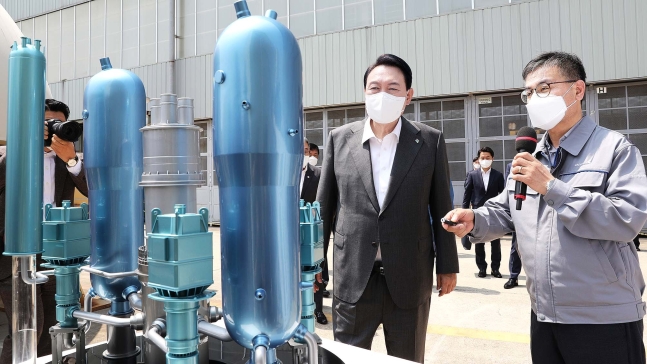 尹錫悦（ユン・ソクヨル）大統領が２２日、昌原の斗山エナビリティ原子力工場を訪問し、キム・ジョンド専務の説明を聞きながら韓国型原子炉ＡＰＲ１４００縮小模型を見ている。　［大統領室写真記者団］