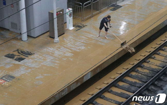 光明駅プラットフォームの泥水を除去している様子。［写真　ニュース１］