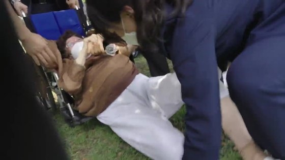 警護員によって椅子からずり落ちる李容洙さん。［写真　日本軍慰安婦問題ＩＣＪ回付推進委員会］