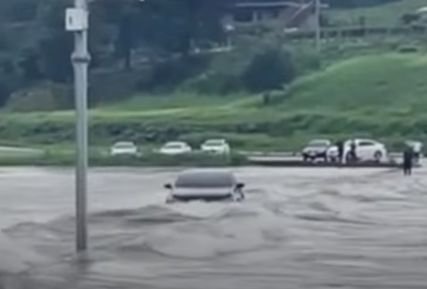 江原道寧越南面の北双橋（ブッサンギョ）を渡っていた車両が川の水に巻きこまれて流された。右端の黒い服を着た人がドライバーだ。［写真　ＹｏｕＴｕｂｅ　キャプチャー］
