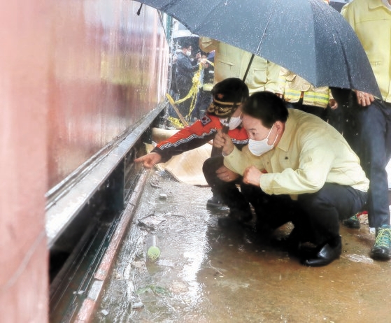 尹錫悦大統領が９日午前、ソウル新林洞で昨夜降った雨で４０代女性と妹および１０代の娘など一家族３人が浸水事故で亡くなった半地下住宅を見ている。［写真　大統領室写真記者団］