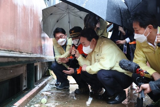 尹錫悦大統領が９日浸水被害死亡事故が発生したソウル新林洞のアパートを訪ねて現場に関する説明を聞いている。［写真　大統領室］