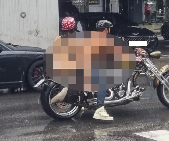 上半身裸の男性がビキニ姿の女性をオートバイの後ろに乗せてソウル市内を走行している様子。［オンライン掲示板　キャプチャー］