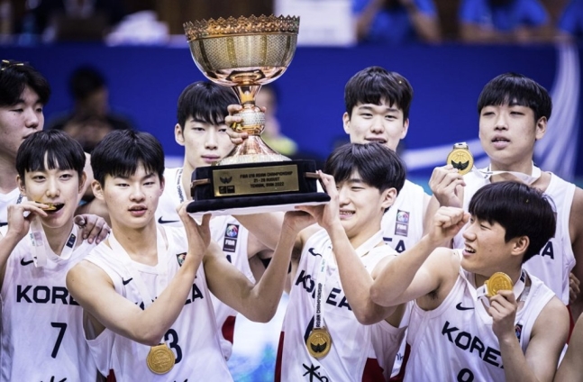 韓国Ｕ－１８バスケットボール代表が２８日、イランで行われたＵ－１８アジアチャンピオンシップ決勝で日本に勝利し、優勝を果たした。姜東熙（カン・ドンヒ）の息子カン・ソンウク（左）ら選手がトロフィーを掲げて喜んでいる。　写真＝ＦＩＢＡ