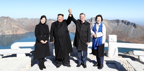 ２０１８年９月２０日、韓国の文在寅（ムン・ジェイン）大統領（左から３人目）と北朝鮮の金正恩（キム・ジョンウン）委員長（左から２人目）が白頭山（ペクドゥサン）将軍峰（チャングンボン）で手を取り合って記念撮影を撮影している様子。写真共同取材団