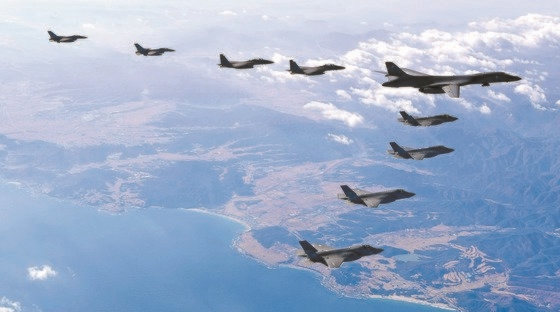 写真は２０１７年１２月６日、韓米連合空中訓練「Ｖｉｇｉｌａｎｔ　ＡＣＥ」に参加した両国空軍の軍用機が韓半島（朝鮮半島）上空で編隊飛行をしている様子。右側は米国の超音速爆撃機Ｂ－１Ｂ「ランサー」。その後方で両国戦闘機が編隊飛行している。左側から韓国空軍「Ｆ－１６」２機、「Ｆ－１５Ｋ」２機、米国空軍「Ｂ－１Ｂ」１機、「Ｆ３５Ａ」２機、「Ｆ３５Ｂ」２機。［写真　韓国空軍］